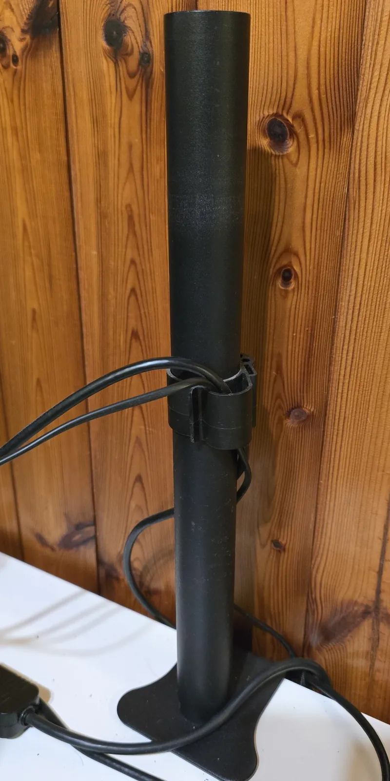 The original black steel pole of the monitor stand on its desk base, before the extension